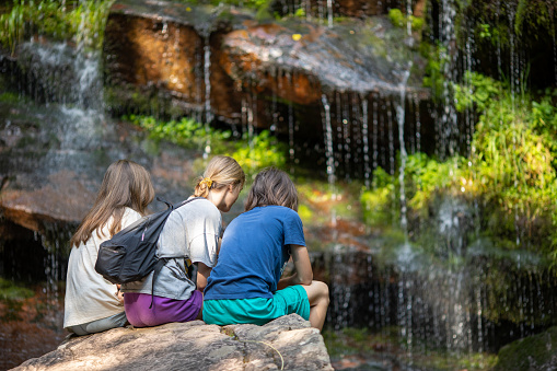 Teenage girls and boy enjoying beautiful landscape with waterfall in the forest on mountain. Tupavica waterfall, Balkan mountains, Serbia