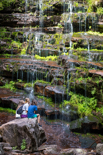 Teenage girls and boy enjoying beautiful landscape with waterfall in the forest on mountain. Tupavica waterfall, Balkan mountains, Serbia