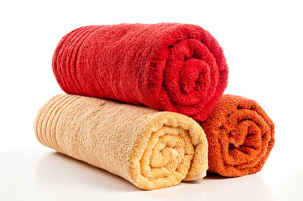 Three rolled bath towels isolated on white, red, orange, yellow