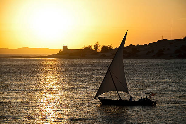 Dhow at Sunset "A dhow sailboat at sunset off the coast of Lamu, Kenya" felucca boat stock pictures, royalty-free photos & images