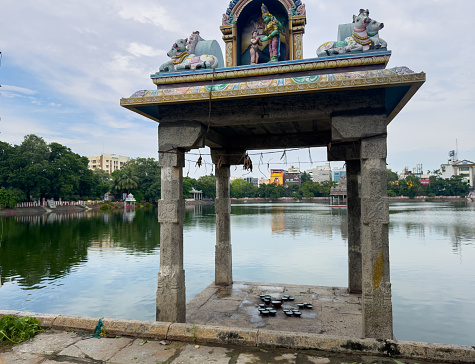 Chennai, Tamil Nadu, India - December 05 2023: Temple tank of Kapaleeshwarar Temple filled to the brim due to the rainfall caused by severe cyclonic storm Michaung. Focus set on the top sculpture.