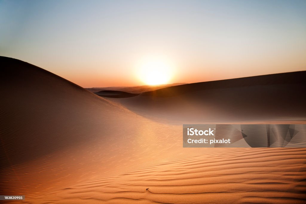 Desert Sunset Rub' al Khali of Abu Dhabi, UAE Sun setting over a horizon with sand dunes in the desert at dusk. Heat Haze Stock Photo