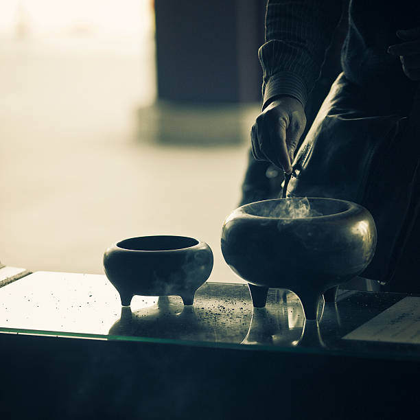detail of a man hand offering incense and praying at the entrance of the Zojo-Ji temple in Tokyo, Japan.