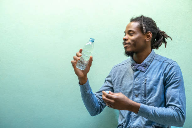 istock A man holding a plastic bottle with water in front of a blue wall. 1838225681