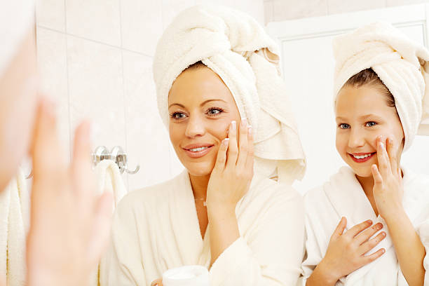 mutter und ihre tochter sind auf gesichtscreme setzen. - mirror mother bathroom daughter stock-fotos und bilder