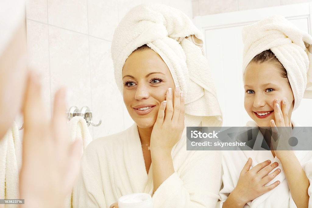 Madre e sua figlia stanno mettendo sulla crema viso. - Foto stock royalty-free di Madre