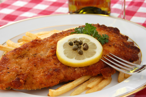 Classic Austrian breaded and fried veal cutlet (could also be pork or chicken) garnished with lemon and capers and served with french fries.More images from this series: