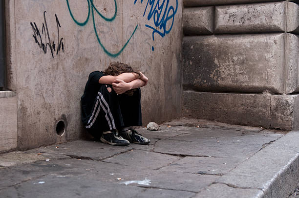 Boy huddled and alone on city street Young boy huddled and alone on a city street in Rome. Related: child abuse photos stock pictures, royalty-free photos & images