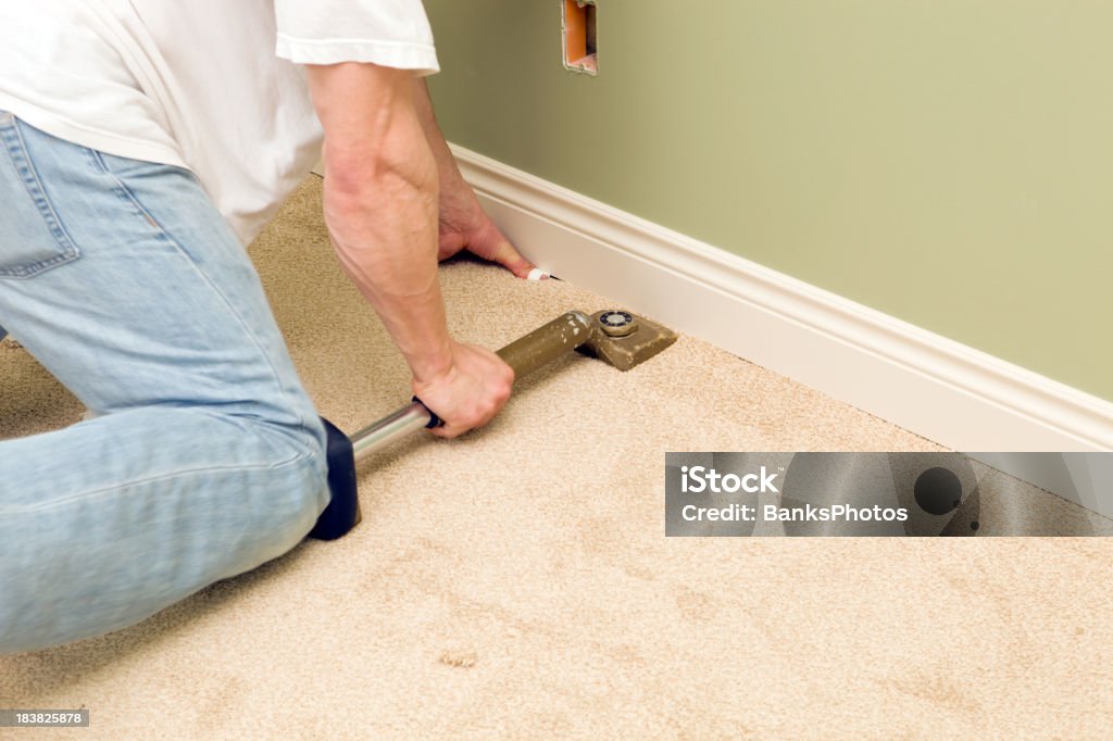 Instalador utilizando la rodilla Kicker para distenderse dormitorio alfombra - Foto de stock de Moqueta libre de derechos