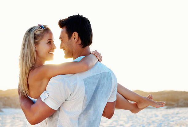 człowiek przewożących kobieta na plaży i uśmiechania się, - beach couple satisfaction playing zdjęcia i obrazy z banku zdjęć