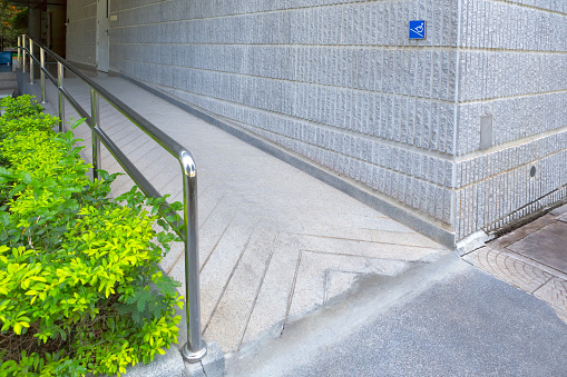 Concret ramp way with stainless steel handrail with disabled sign for support wheelchair disabled people.