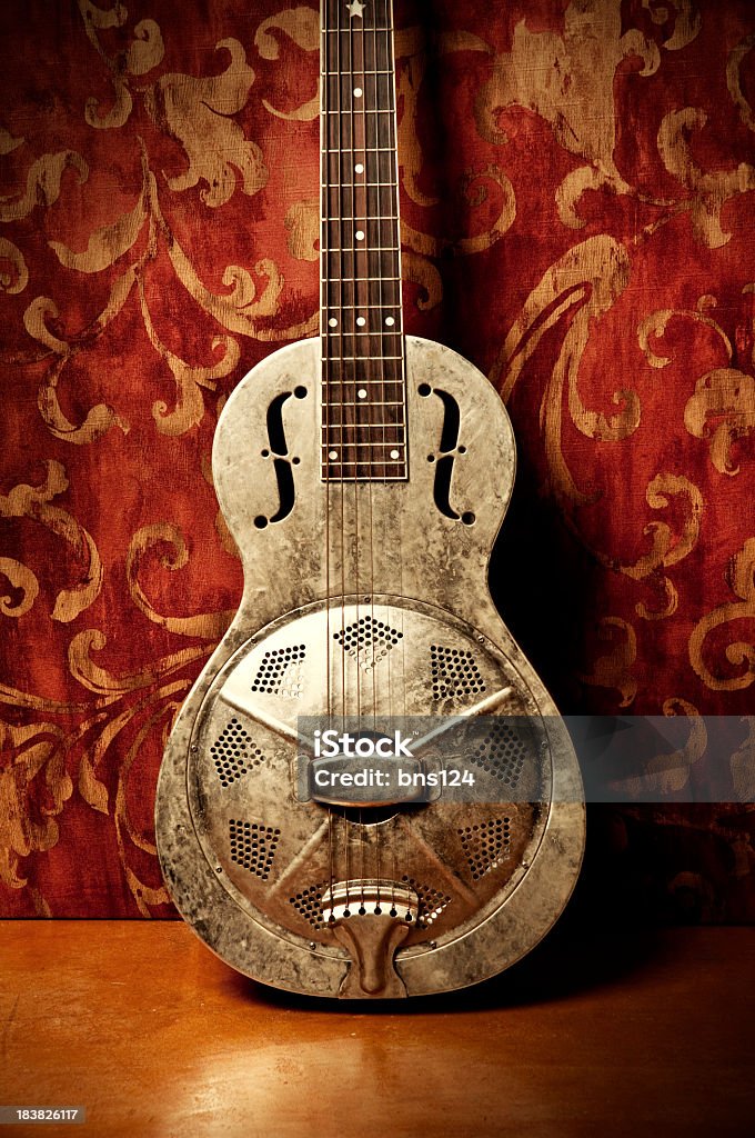 Gold acoustic guitar with red floral wallpaper Resonator Guitar on Red Background  Arts Culture and Entertainment Stock Photo