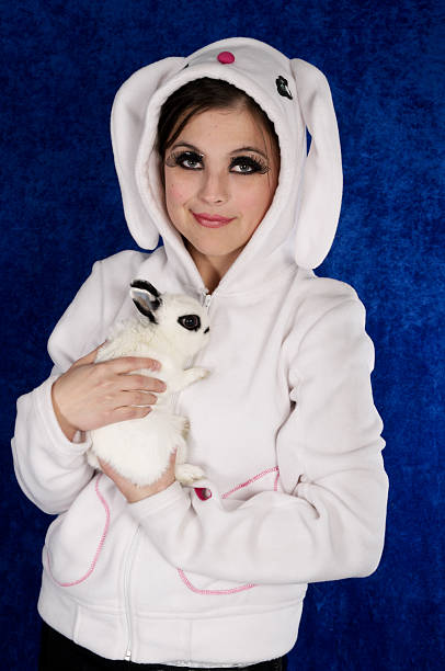 istock Young woman in bunny hoody holding rabbit. 183826178