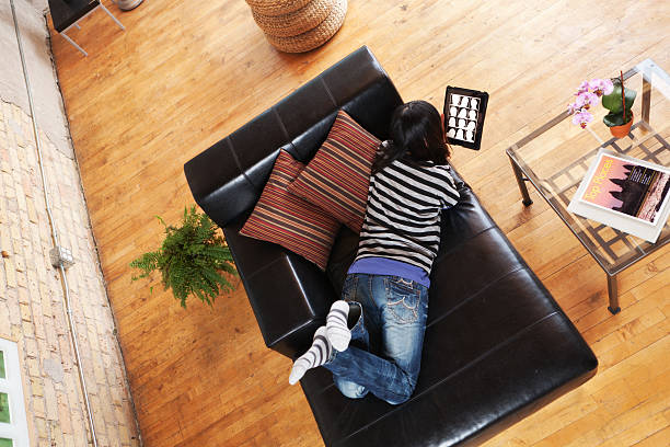 Subject: A young woman using tablet computer for social networking and connecting with friends, in her loft apartment condominium home.