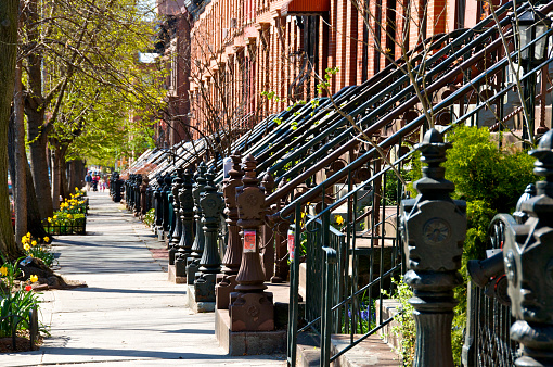 A row of late 19th century Brownstone homes in a Historic Landmark district of Park Slope, Brooklyn, New York City photographed on a sunny afternoon. An example of desirable real estate, urban density and old fashioned architecture.