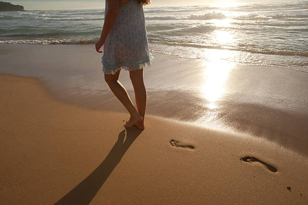 istock Woman strolling on beach at sunset 183827369
