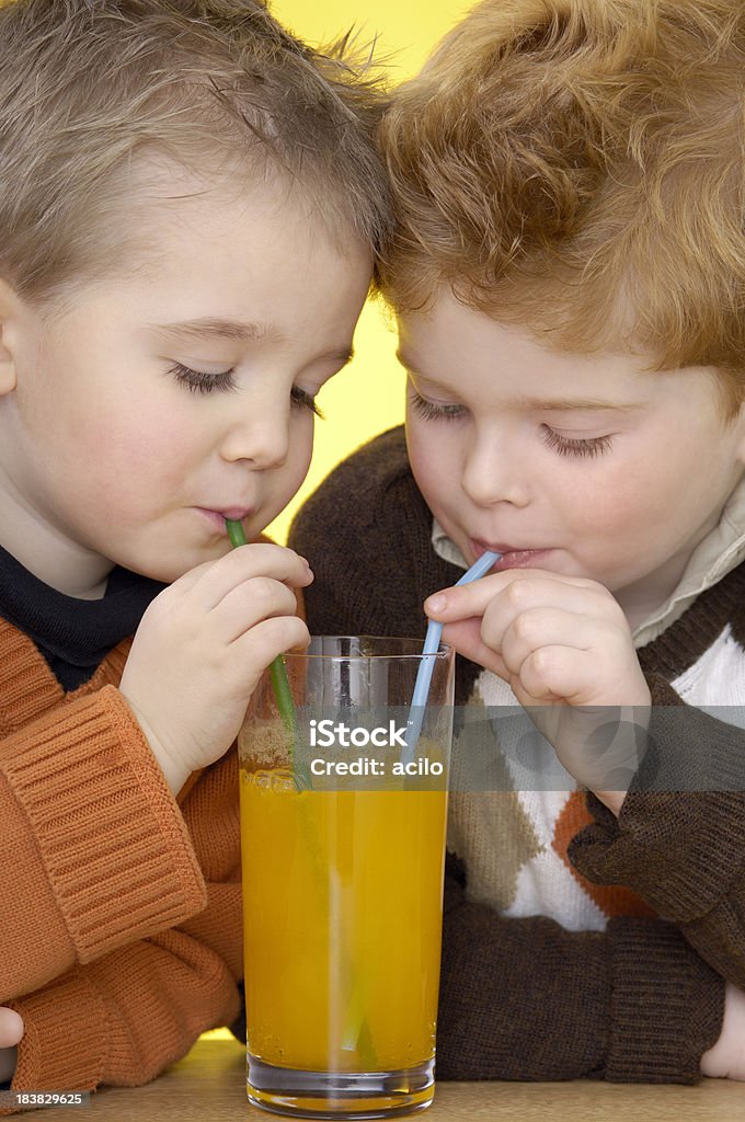 Dwa cute chłopców są picia pomarańczowy Lemoniada - Zbiór zdjęć royalty-free (Pić)
