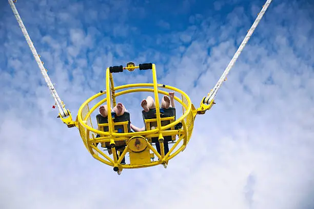 Tow people with bare feet are catapulted into the sky on a Twin Bungee Rocket Ride at Amusement Park