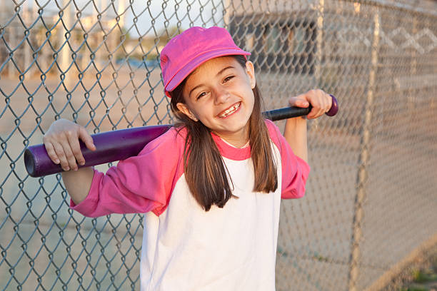 Adorable little baseball girl laughing and smiling as she takes a break after practice.