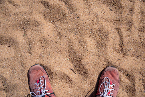 Two red shoes in the sand photographed from above. High quality photo
