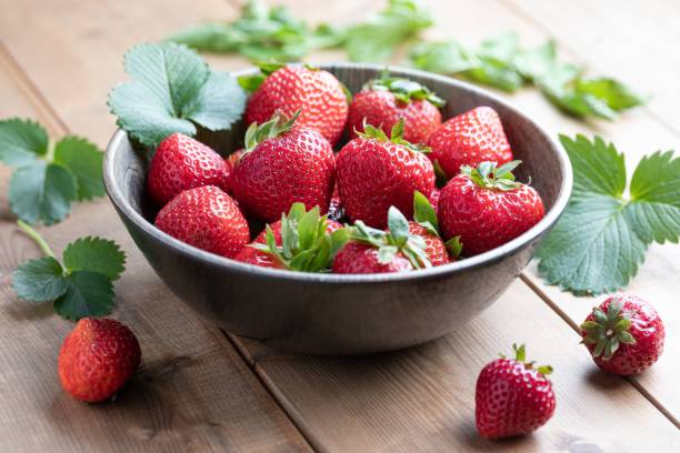 istock Rustic wooden table featuring a bowl filled with ripe red strawberries 1838318160