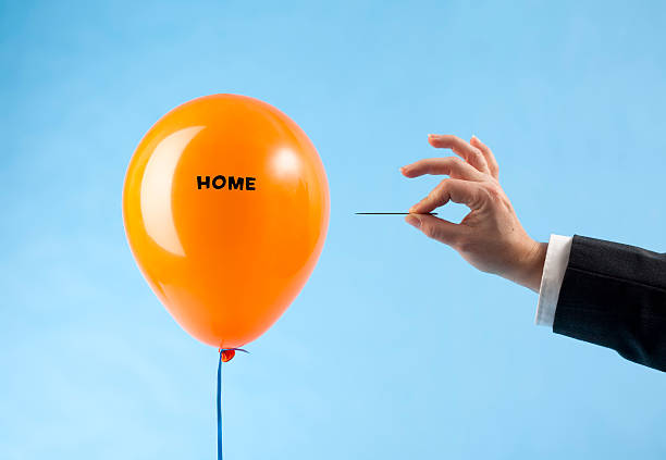 istock 'Home' balloon attacked by hand with needle 183832164