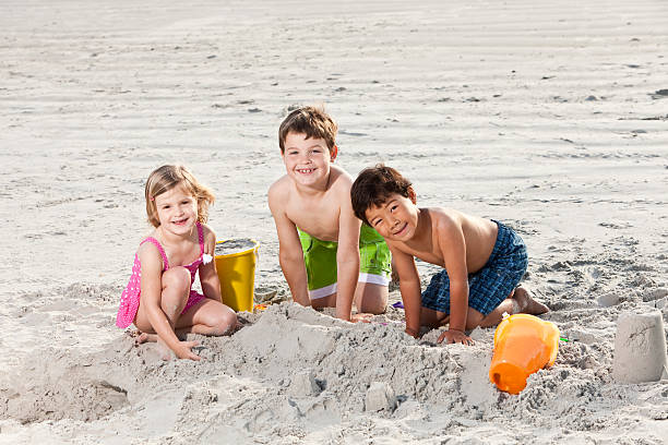 istock Multiracial friends playing in sand at the beach 183833593