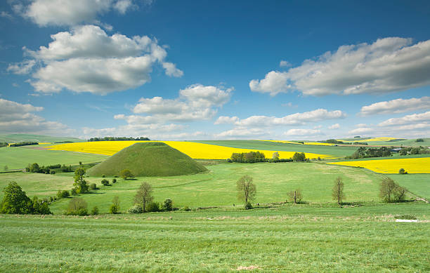 Silbury Hill The fantastic Silbury Hill near Avebury and Stonehenge in Wiltshire. This photograph was made in early summer with oilseed rape fields in the distance. This area is a world heritage site. burial mound photos stock pictures, royalty-free photos & images