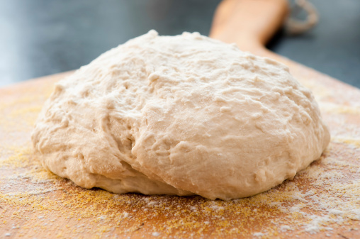 A blob of homemade raw  bread (bouche) dough sits on a peel.