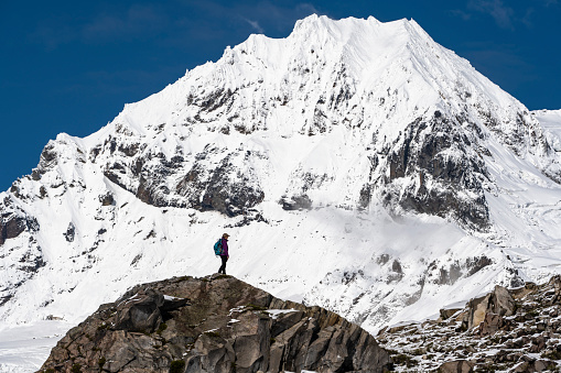 Hiker pauses on ridge below snowcapped mountains and looks out