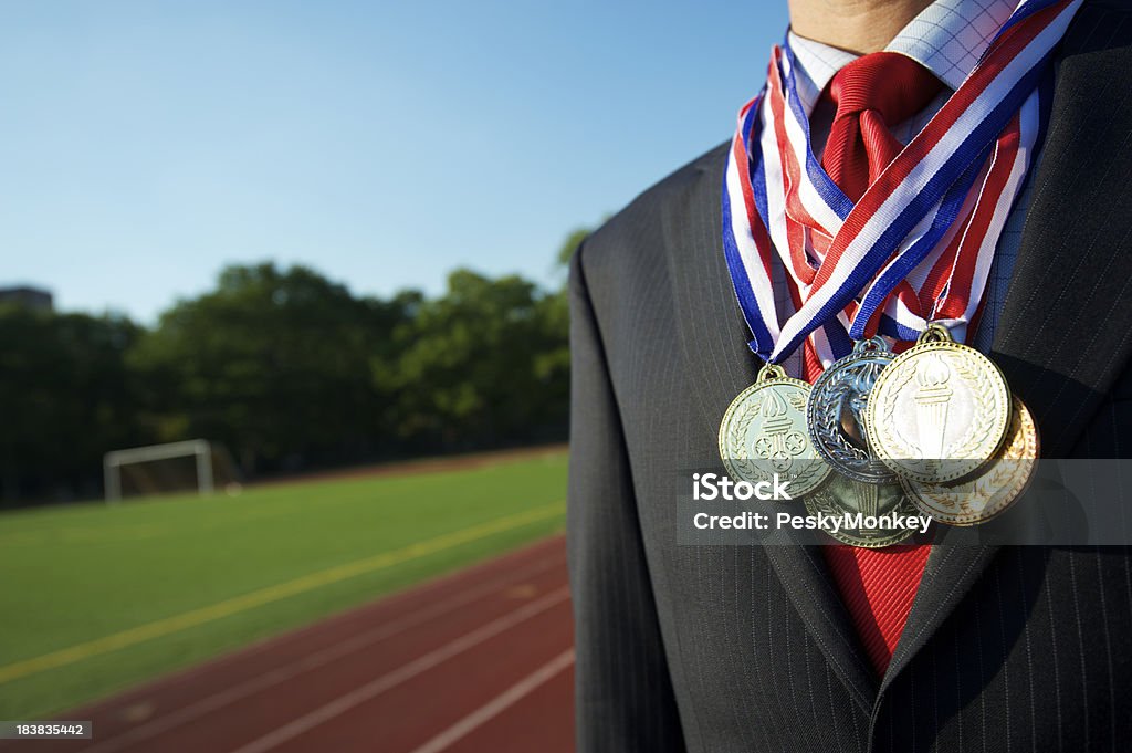 Exitoso hombre de negocios de pie decoradas con medallas por pista de atletismo - Foto de stock de Medalla libre de derechos