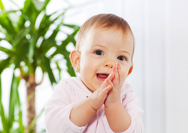 Funny laughing baby girl playing on a green blanket