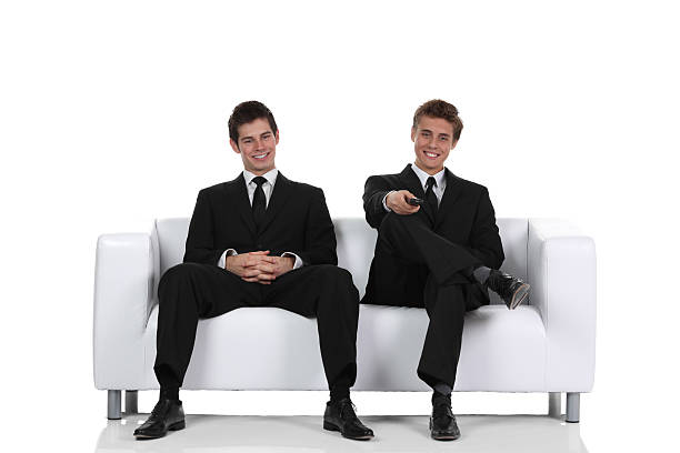 Two businessmen in suits are arguing and three are sitting, discussing business strategy, teamwork, collaboration, office environment, corporate discussions.