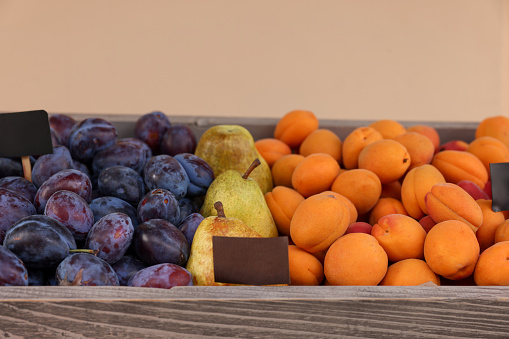 Fresh ripe fruits in wooden crate at market, closeup