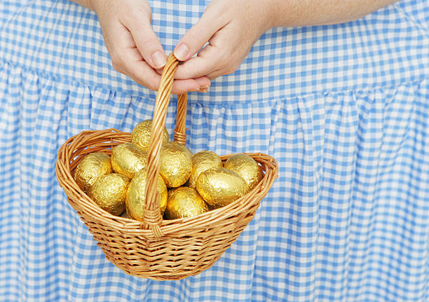 Photo showing a pile of rainbow coloured foil wrapped chocolate Easter eggs that are piled up in a round wicker basket, ready to be placed around the garden for a seasonal Easter egg trail.