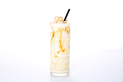 Caramel milkshake with straw served in glass isolated on grey background side view of healthy morning arabic drink