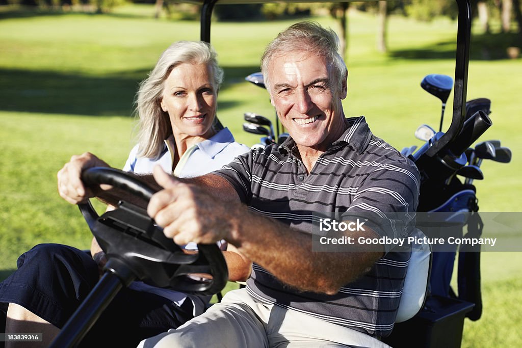 Smiling couple in a golf cart Portrait of a mature golfing couple sitting in a golf cart and smiling Golf Stock Photo