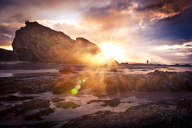 Waves can be seen crashing into rocks nearing sunset in Iceland.