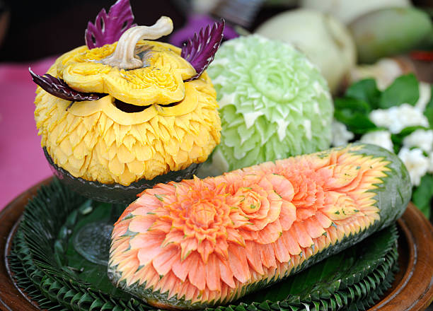 Songkran, Thai Fruit Art In Thailand the New Year is celebrated with the Songkran Festival. Here a lady has carved flowers in watermelons. This art has all been carved out of one piece. Very impressive! Shallow focus. fruit carving stock pictures, royalty-free photos & images