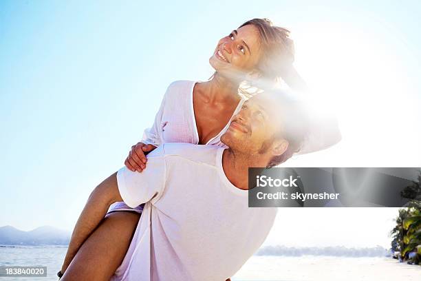 Happy Couple On The Beach Doing Piggy Back Ride Stock Photo - Download Image Now - Activity, Adult, Adults Only