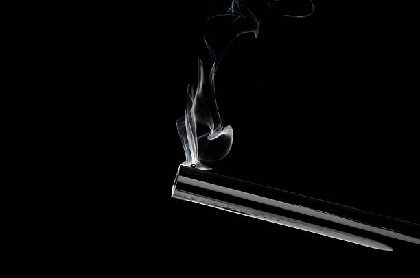 Back-lit barrel of a gun still smoking.