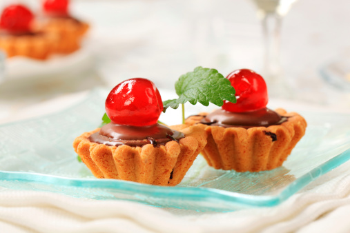 Chocolate filled tartlets garnished with maraschino cherries