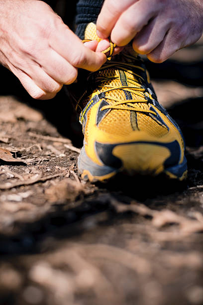 A person tying their yellow hiking shoes stock photo