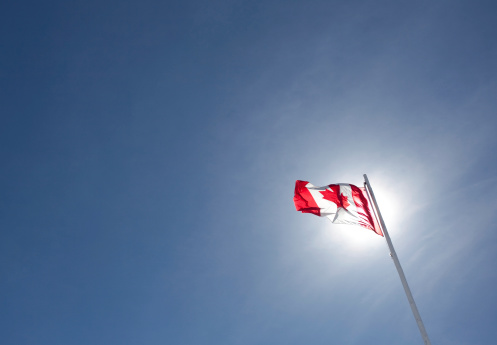 The Canadian flag with sun and blue sky. Lots of copyspace.