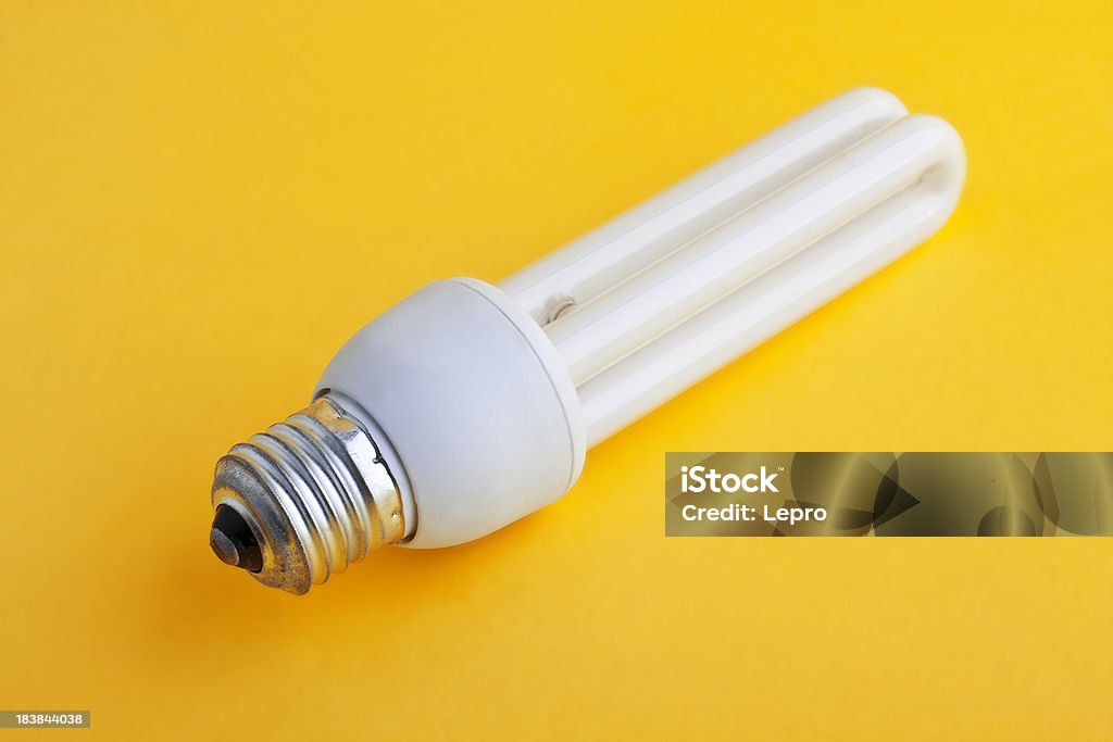 Fluorescent Illuminated fluorescent light bulb on yellow background. Clean Stock Photo