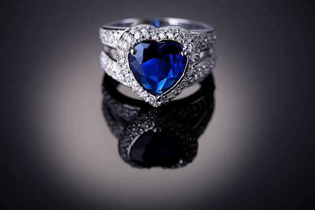 Detail of a silver ring with a blue heart-shaped gem center Elegance luxury ring with blue heart shaped sapphire. Small amount of noise added in post procesing for better look of background gradient. saphire photos stock pictures, royalty-free photos & images