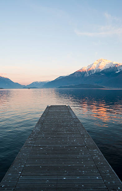 jetée en bois au coucher du soleil sur le lac de côme - como mountain horizon landscape photos et images de collection