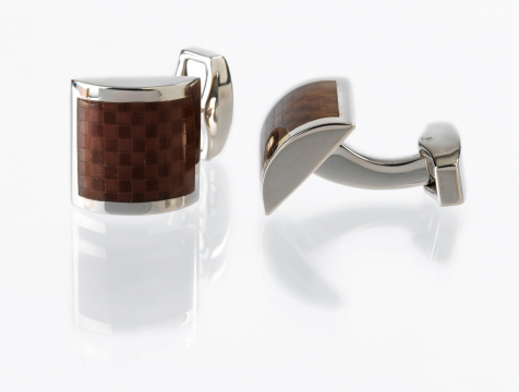 Cuff links with reflection on white background.