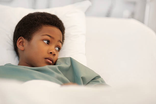 Little boy in the hospital A little boy of african decent looking to the side and lying in a hospital bed. There is ample copy space.Please click on an sick child hospital bed stock pictures, royalty-free photos & images