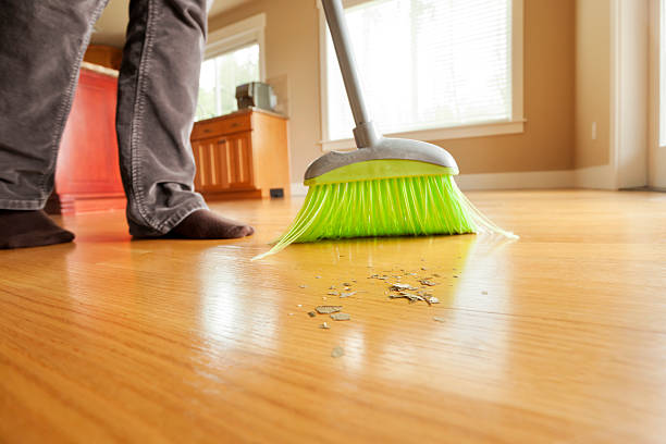 Person Sweeping Mess on Hardwood Floor with Broom stock photo
